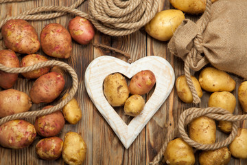 Raw potato food . Fresh potatoes in an old sack on wooden background. Free place for text. Top view