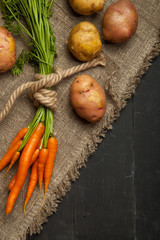 Carrots and potatoes on a black wooden background