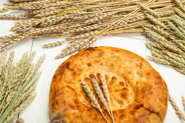 Bread flat cake and wheat on a white wooden background