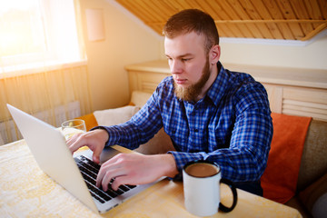 Relaxed young professional surfing the Internet on his laptop in a a dining room