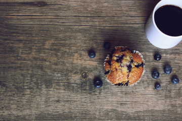 Still life with blueberry muffin, coffee, and blueberries over rustic wooden background, copy space, horizontal
