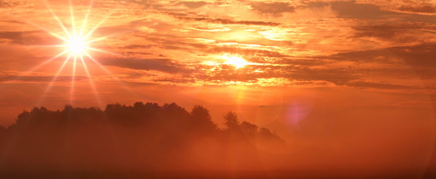 Fototapeta orange sunrise over meadow with morning mist