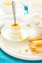 Traditional breakfast: soft-boiled eggs, green tea and bread sticks on white wooden desk. Selective focus