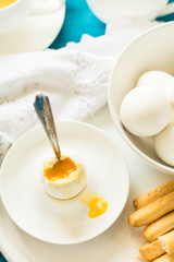 Traditional breakfast: soft-boiled eggs, green tea and bread sticks on white wooden desk. Selective focus