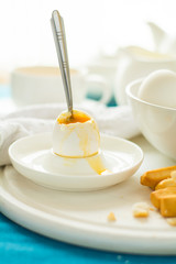 Traditional breakfast: soft-boiled eggs, green tea and bread sticks on white wooden desk. Selective focus