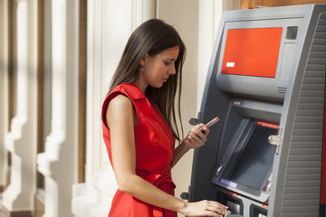 Happy woman withdrawing money from credit card at ATM