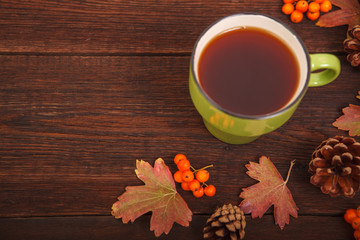 Autumn concept, fallen red-yellow leaves with apples, pine cones and a cup of tea on a wooden table. Thanksgiving Day.