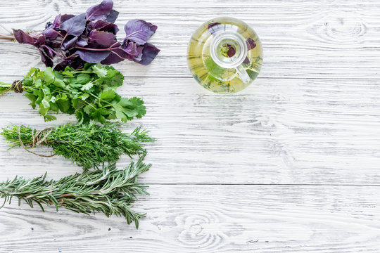 greenery with natural oil for cooking on light wooden kitchen table background top view mock-up