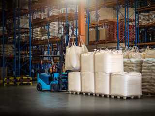 Forklift is handling jumbo bags in large warehouse.