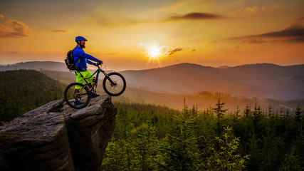 Mountain biker cycling in autumn mountains forest landscape. Man cycling MTB flow trail track. Outdoor sport activity.