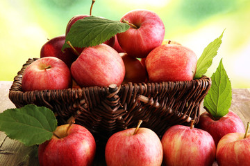 Ripe red apples with leaves on wooden background