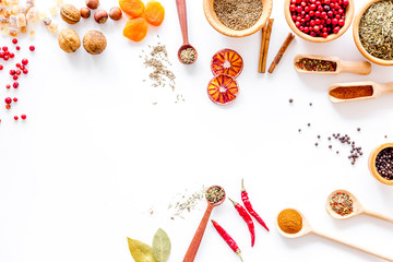 Kitchen table with spices and dry herbs on white kitchen background top view mock up