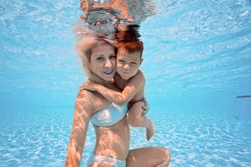 Happy young mother hug her son underwater, swim and dive, breast stroke with fun in pool. Active...