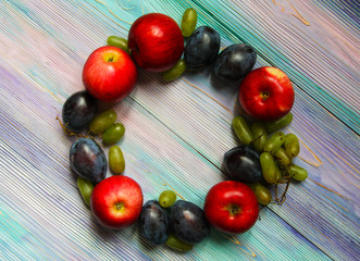 Apples, plums and grapes on a soft blue background