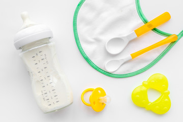 preparation of mixture baby feeding with infant formula powdered milk in bottle with bib on white background top view