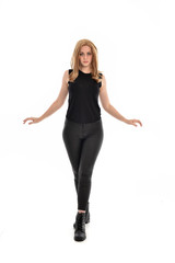 Fototapeta premium full length portrait of girl wearing black clothes and long leather jacket. standing pose in white background.