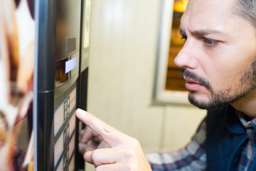 man pressing a vending machine