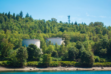 Photo of industrial site behind trees across water