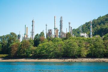 Photo of industrial site behind trees across water