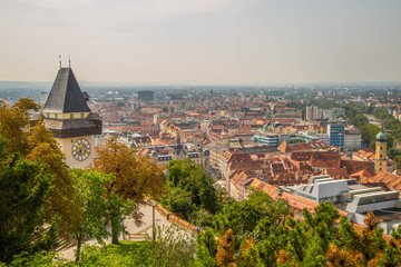 Fototapeta na wymiar Uhrturm Graz im Sommer mit Blumengarten und Stadtpanorama