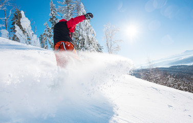 Horizontal low angle shot of a snowboarder riding the slope on a sunny winter day in the mountains....