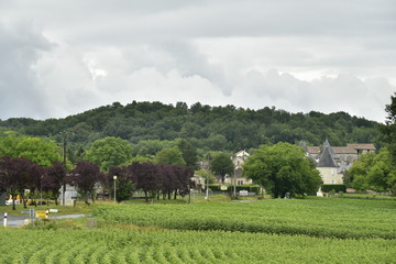 Fototapeta na wymiar Le village de Champagne avec son château et son église romane derrière les champs ,après une averse, au Périgord Vert 