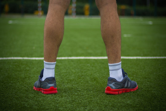 Image of male legs in sneakers on an artificial football field