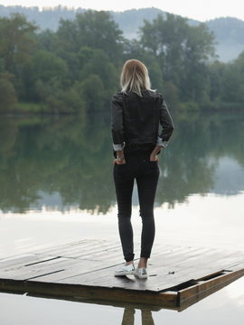 Back view of blonde woman in casual clothes on wooden pallet ove