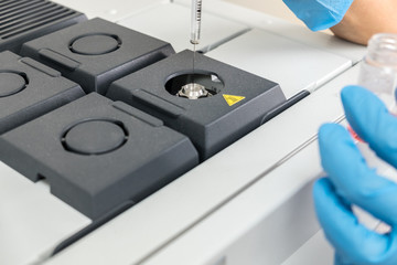 The scientist woman hands in gloves, during test on mass spectrometer in chemistry lab