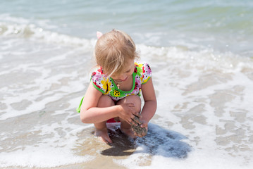 A child, a little girl playing fun on the seashore in the summer.