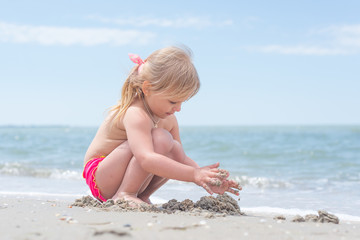 A child, a little girl playing fun on the seashore in the summer.