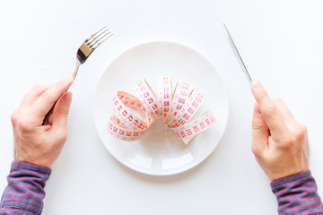 man eating a measuring tape in a plate on a white background