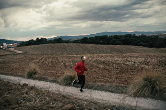 African american man running on a field path at evening.