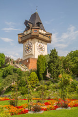 Uhrturm Graz im Sommer mit Blumengarten und Stadtpanorama