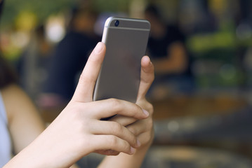 close-up of a girl taking pictures of herself on a gray phone in daylight. background blur