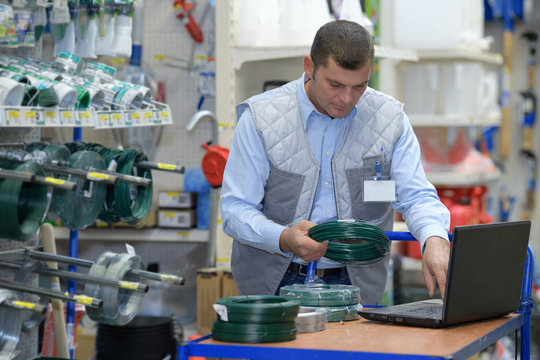 handsome seller using laptop in hardware store