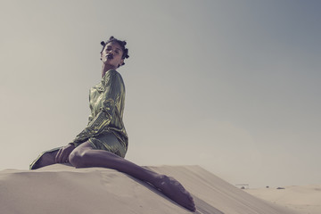 Black model sitting on Sand Dune