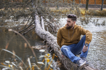 Man sitting on a fallen log in the river.