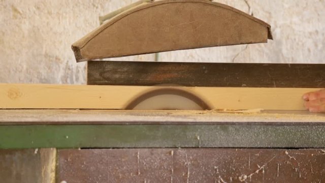 Sawing the wooden square beam on circular saw 