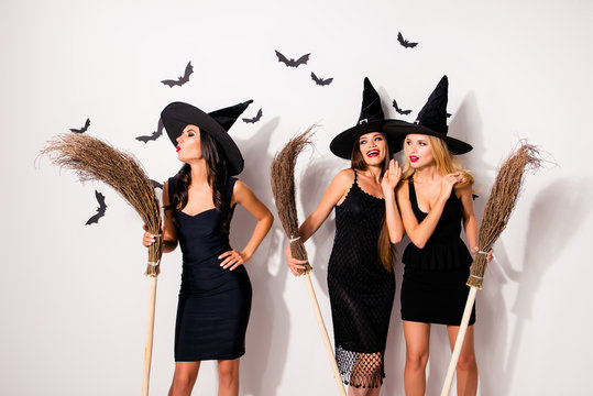 Group of three hot mysterious scary elegant wizards, holding brooms, doind conjure, blow with pouted red lips, doing dark devil demon magic, grinning, enjoying together, on background with bats
