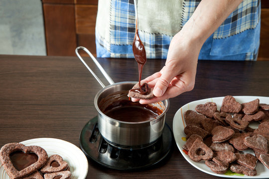 a woman in a home kitchen makes cookies, spreads them with caramel