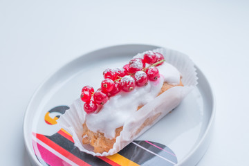 Eclairs glazed with berry. Chocolate eclairs and red currants isolated on white background. Copy space