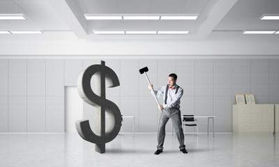 Determined banker man in modern office interior breaking dollar figure