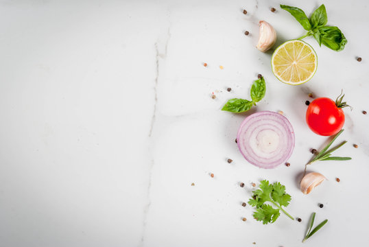 Food cooking background, white marble kitchen table. Spices and herbs for cooking dinner - coriander, parsley, basil, rosemary, lime, tomato, salt, pepper, garlic, onion, tomato. Copy space top view