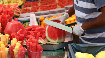 man cuts watermelon with a large and sharp knife to prepare frui