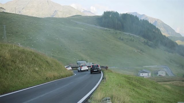 Cars move countryside mountain road on misty morning slow motion. Three automobiles move one by one slowly along serpentine road lane with rails sunrise fog field meadow. Vehicles travel trip journey