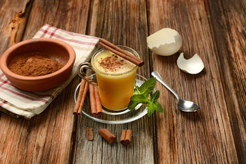 eggnog into glass cup on wooden table
