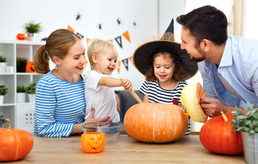 Fototapeta premium happy family mother father and children cut pumpkin for halloween