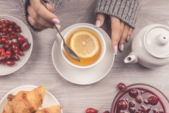 Woman's hand holding cup of tea with lemon on a cold autumn or winter day