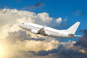 Fototapeta na wymiar Passenger white airplane takes off against a background of cumulus clouds at sunset